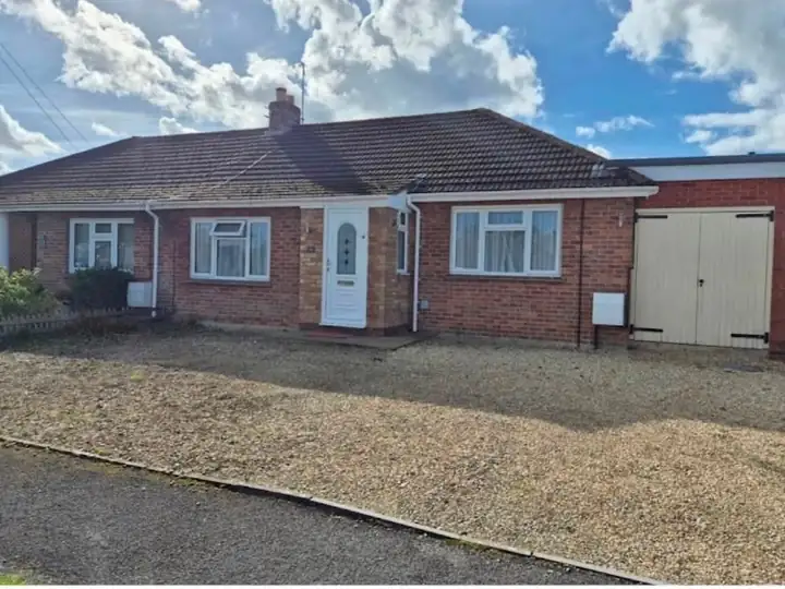 Bungalow with a worn gravel driveway before the work