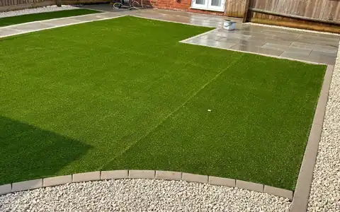 Artificial lawn with a sandstone patio and gravel border