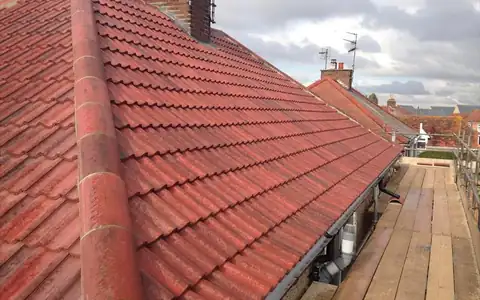 Pitched tiled roof under repair with scaffolding